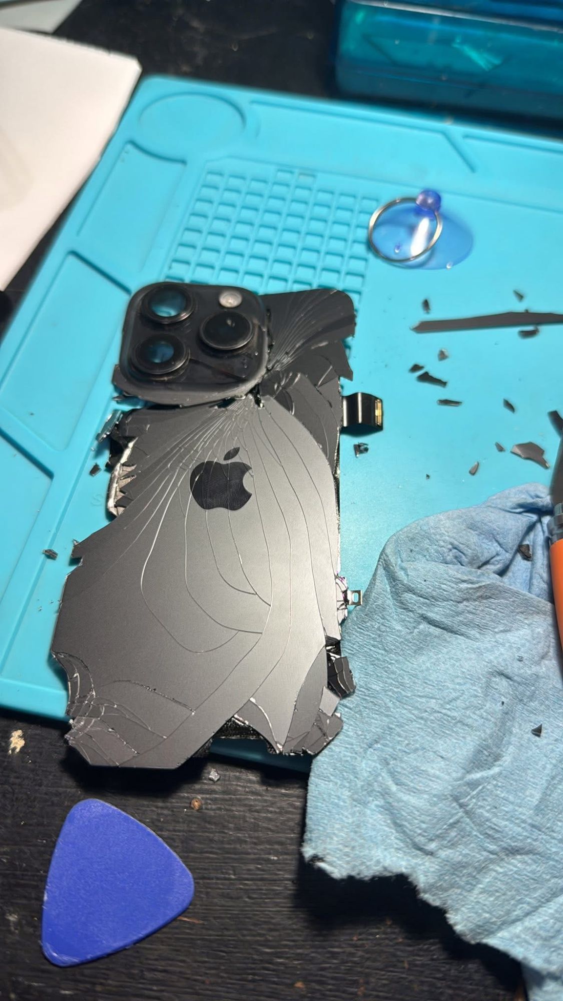 iPhone Pro with shattered back glass on a repair mat